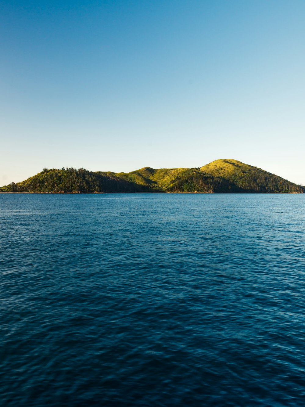 green mountain beside body of water during daytime