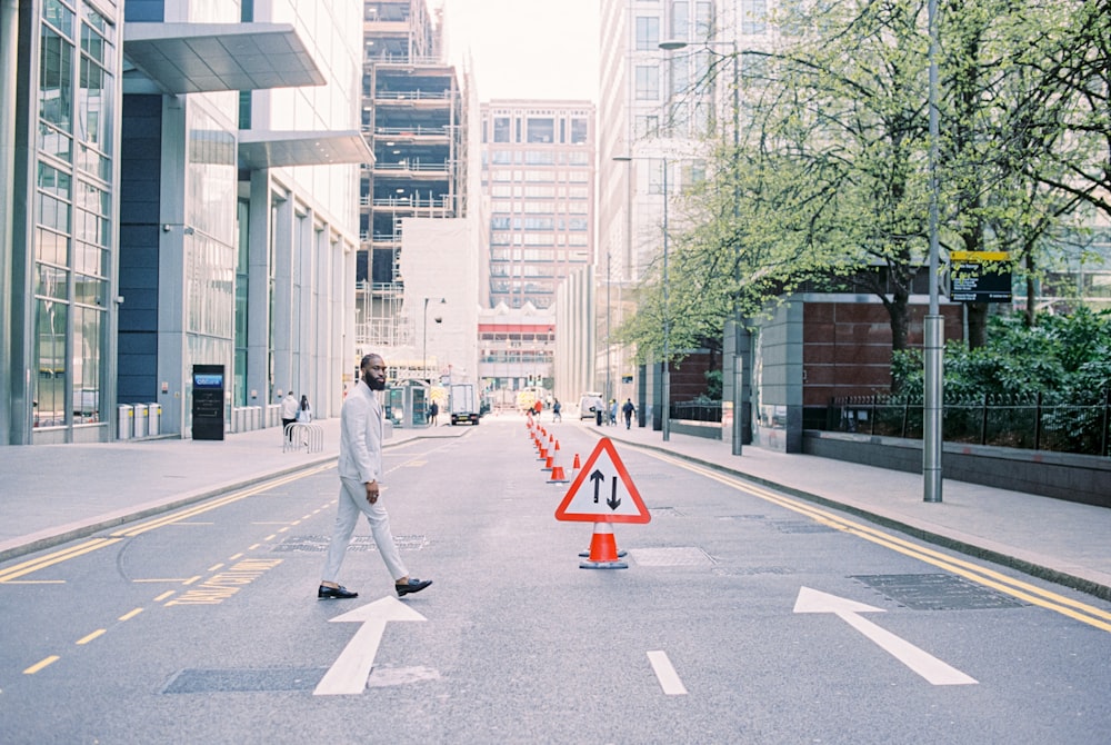 man in gray jacket and gray pants walking on pedestrian lane during daytime