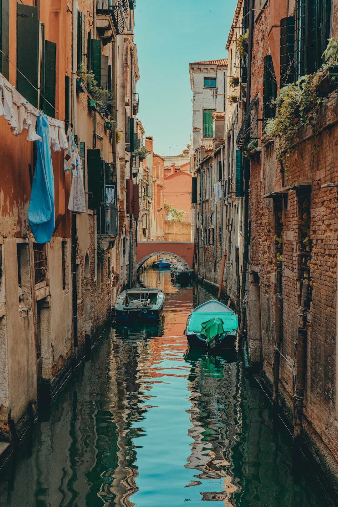 blue boat on river between brown concrete buildings during daytime