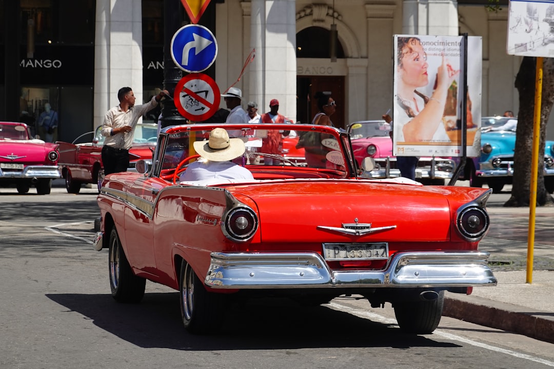 people riding red convertible car during daytime