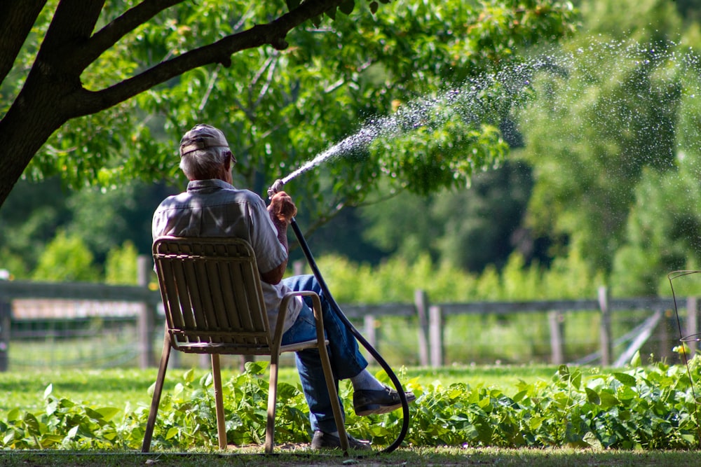 hombre con camisa de rayas azules y blancas sentado en un sillón de madera marrón