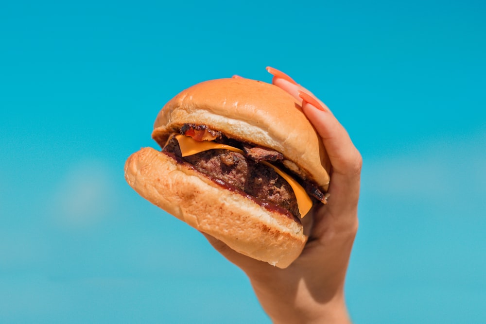 person holding burger with patty and lettuce