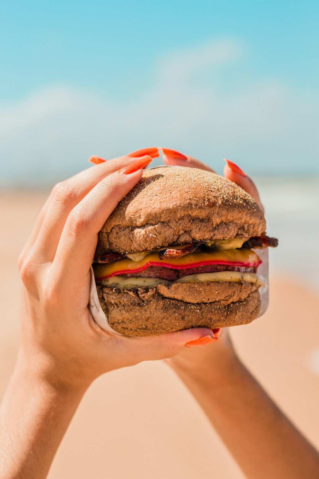 person holding burger with patty and lettuce