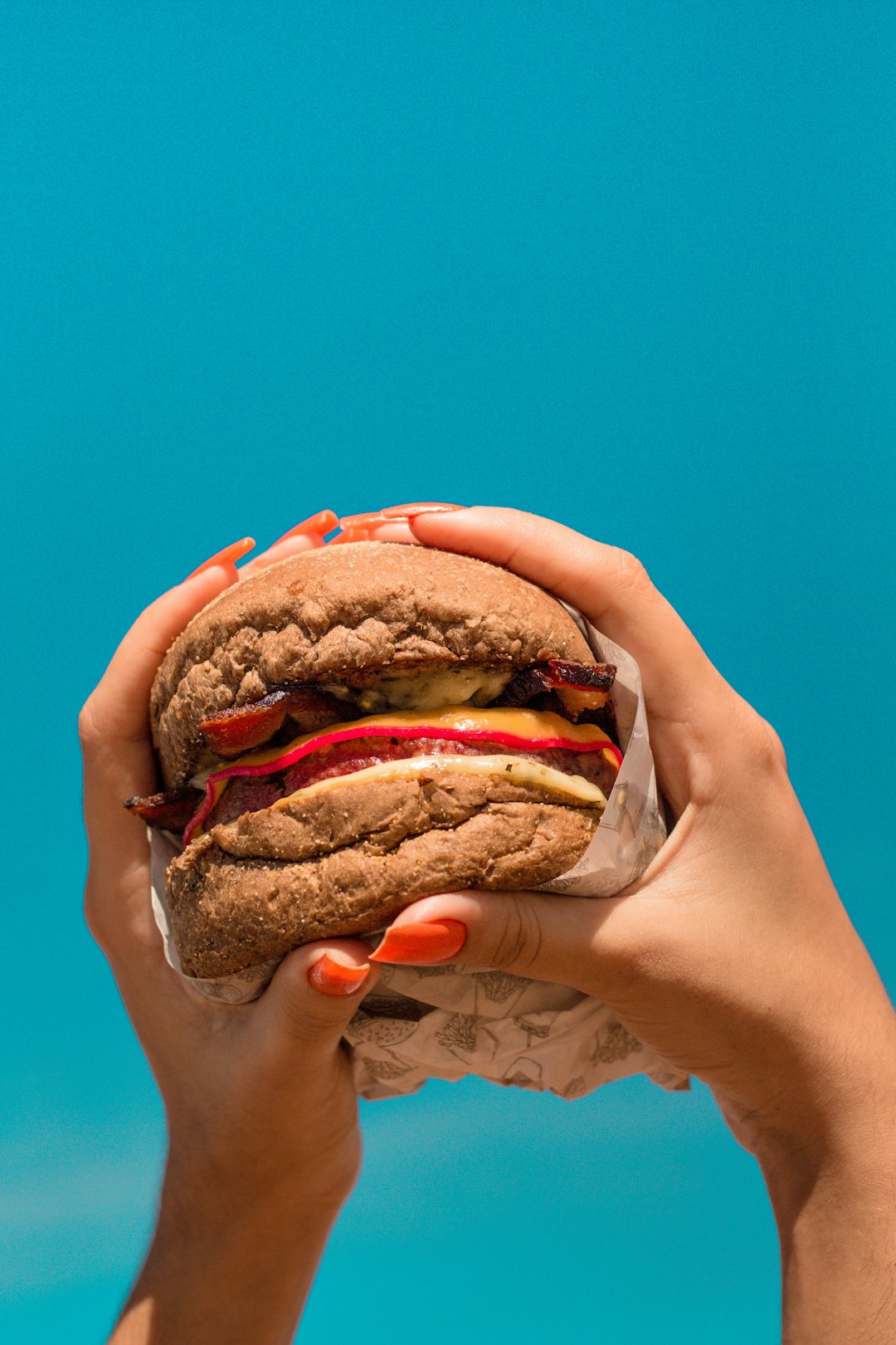 person holding burger with patty and lettuce