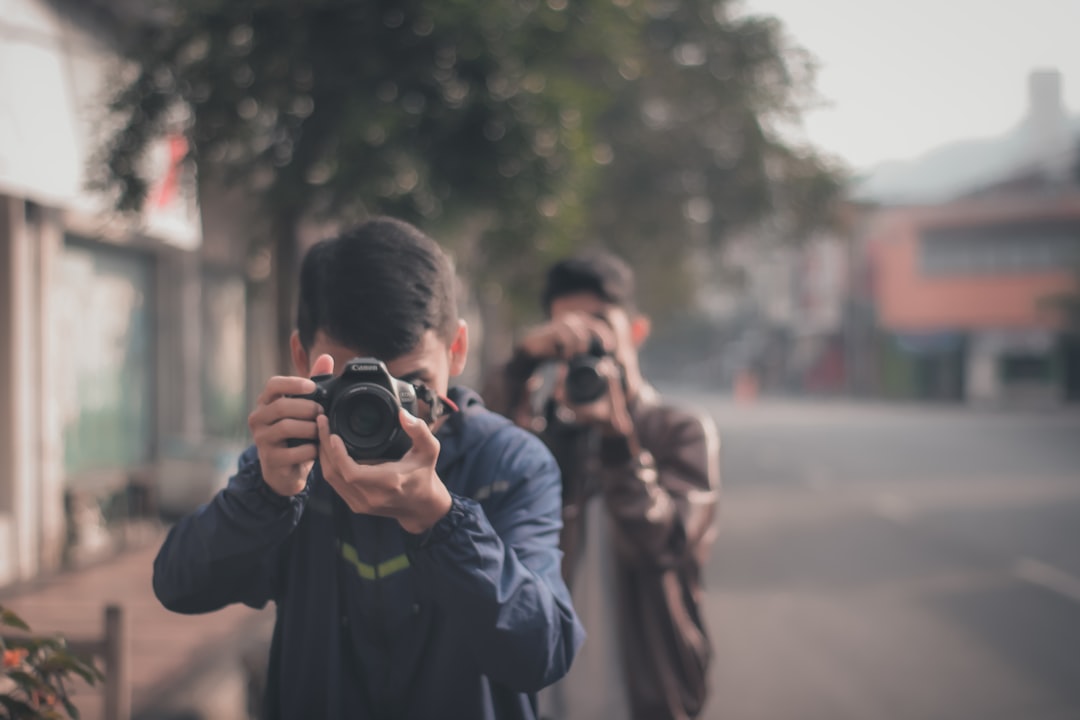 man in black jacket holding black dslr camera, Two Photographer Take Photo