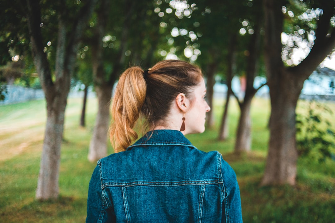 woman in blue denim jacket standing near trees during daytime