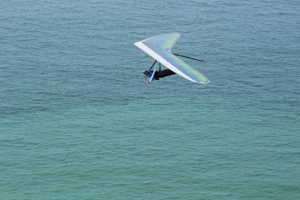 man in black wet suit riding white and purple surfboard on sea during daytime