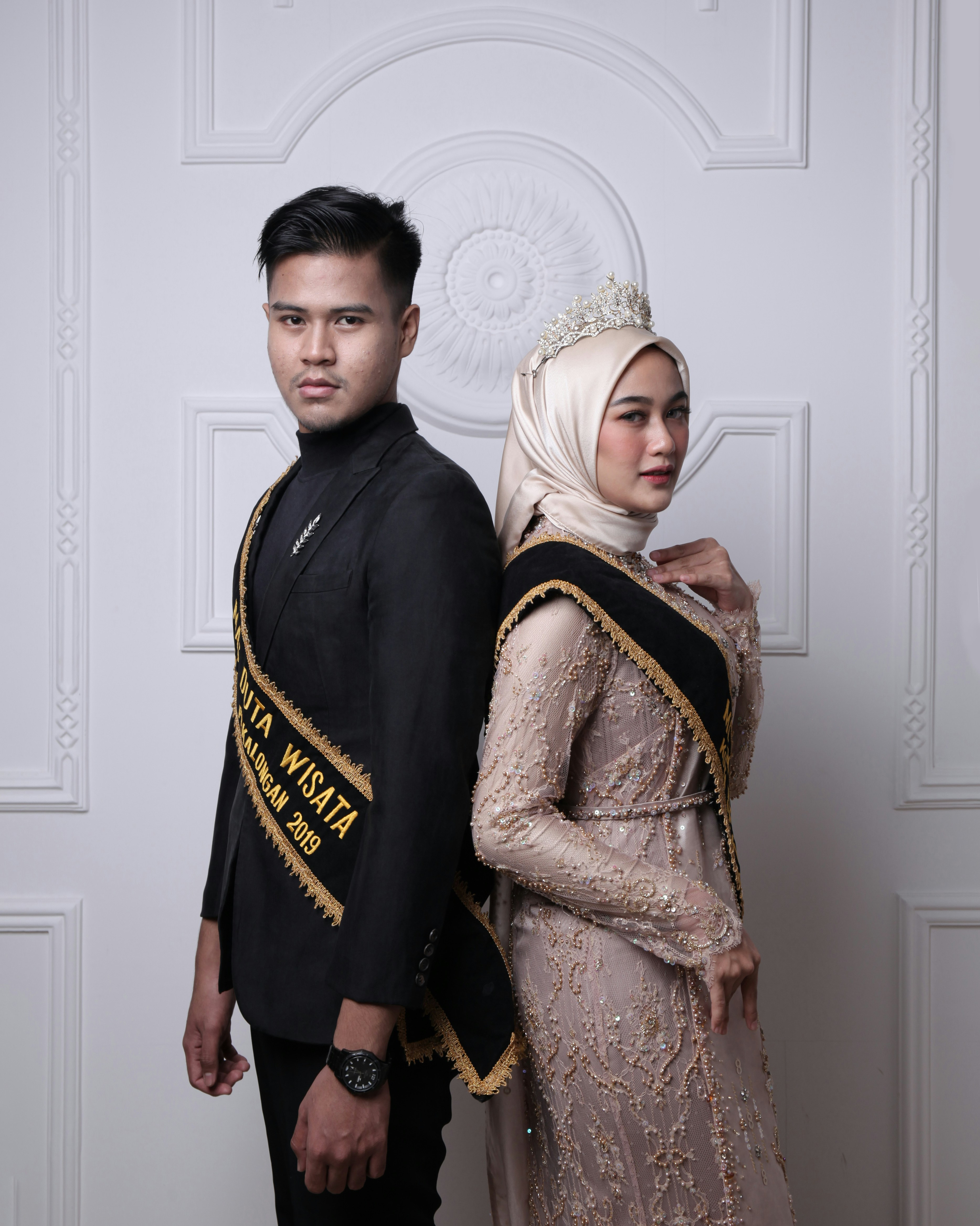 hombre en chaqueta negra y amarilla al lado de la mujer en vestido floral marrón