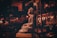 A dimly lit scene featuring a metallic statue of Buddha sitting in a serene pose. The background includes a Tuk-Tuk vehicle adorned with lights and a sign with text in Thai script. The overall ambiance is warm with an emphasis on reflective surfaces and intricate patterns.