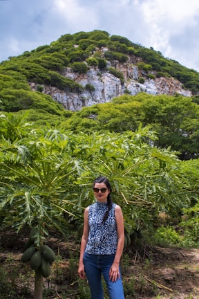 A woman smiling gently while caring for papaya plants in a small farm.