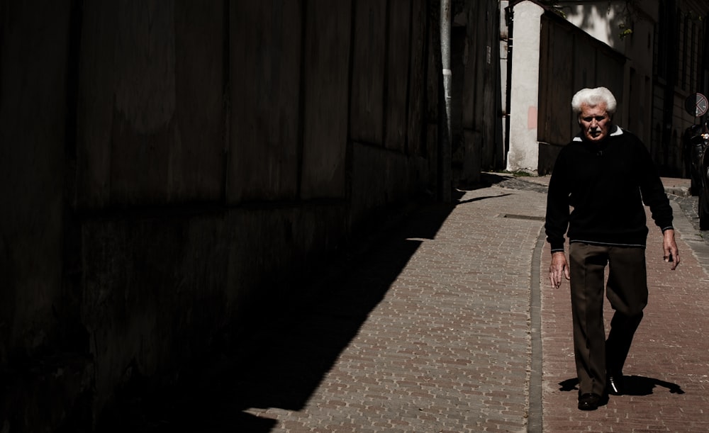 woman in black jacket walking on sidewalk during daytime