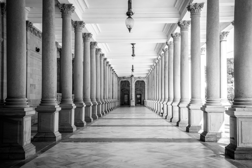 Photo en niveaux de gris d’un couloir avec des colonnes