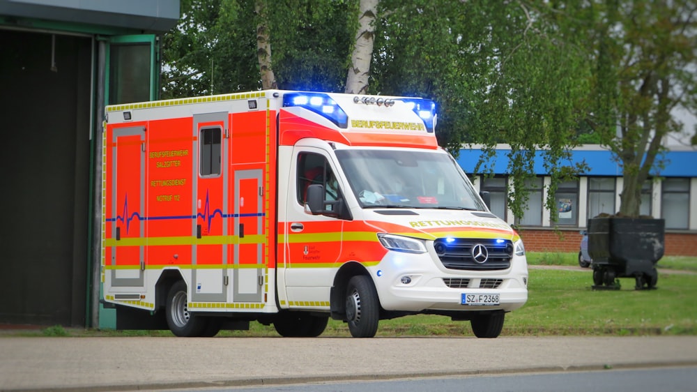 white and red ambulance parked on gray pavement