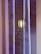 A decorative wall with intricate line art of floral patterns in shades of brown and gold, illuminated by soft blue lighting. A modern pendant light fixture hangs in front of the wall, casting a warm glow.