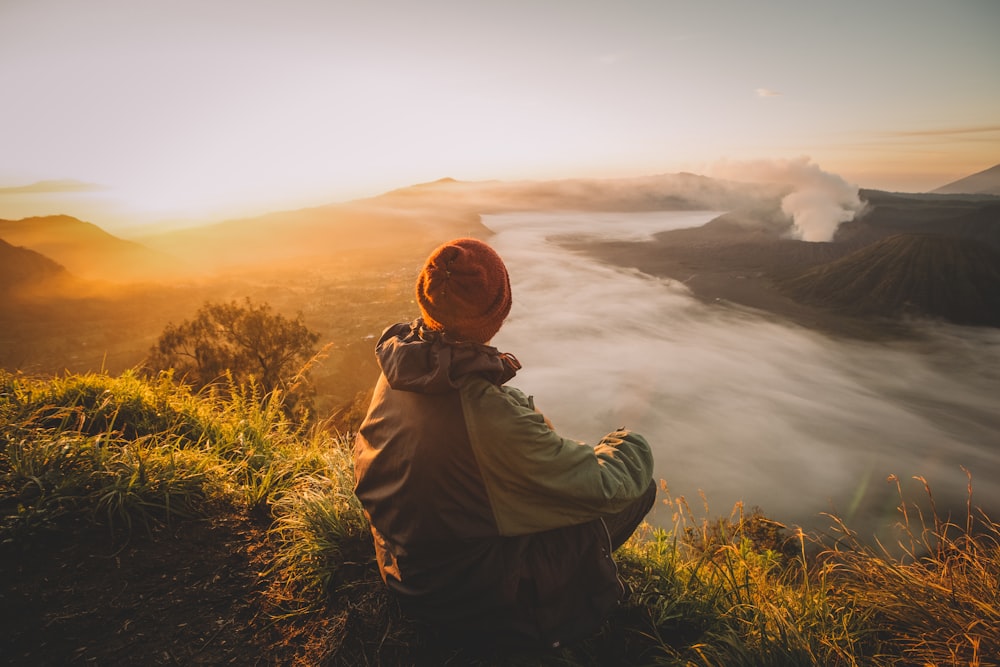 man in gray jacket taking photo of sunset