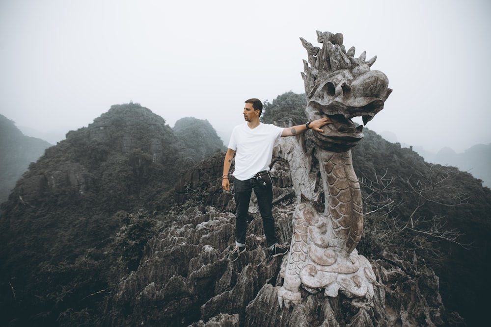 man in white t-shirt standing beside woman statue