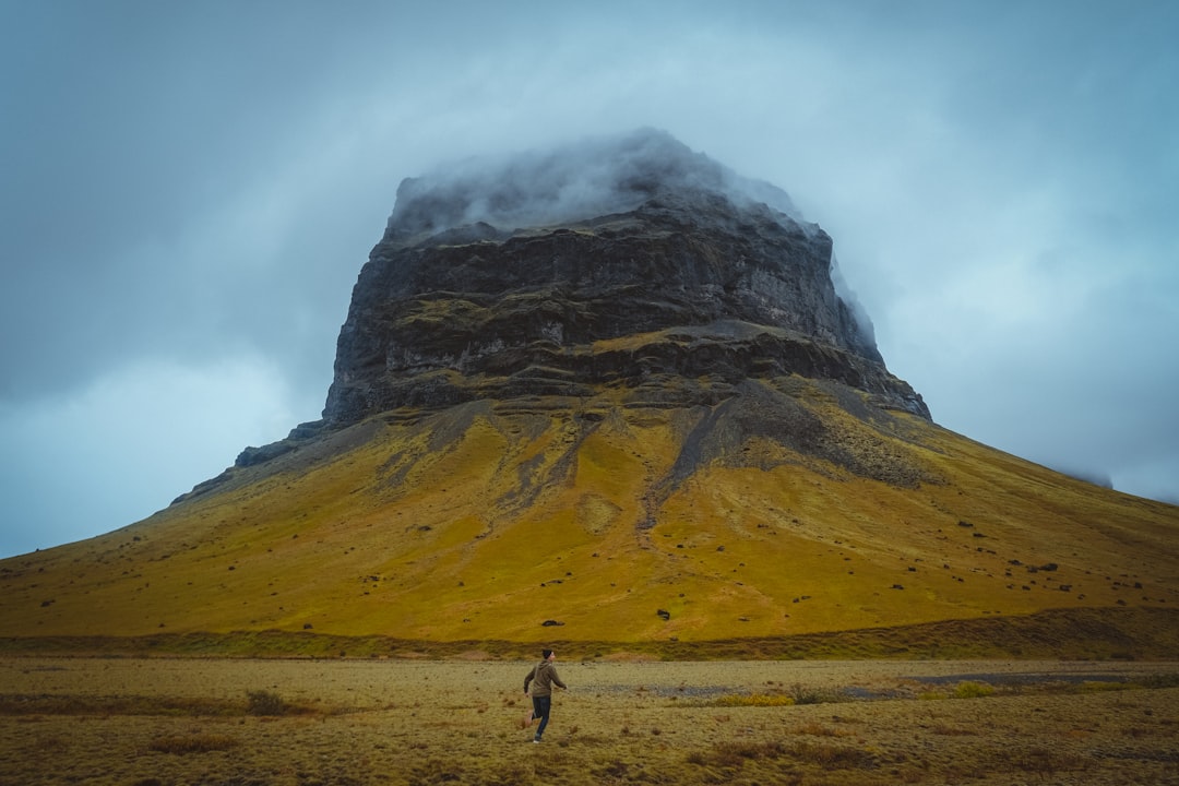 person walking on brown field near mountain during daytime