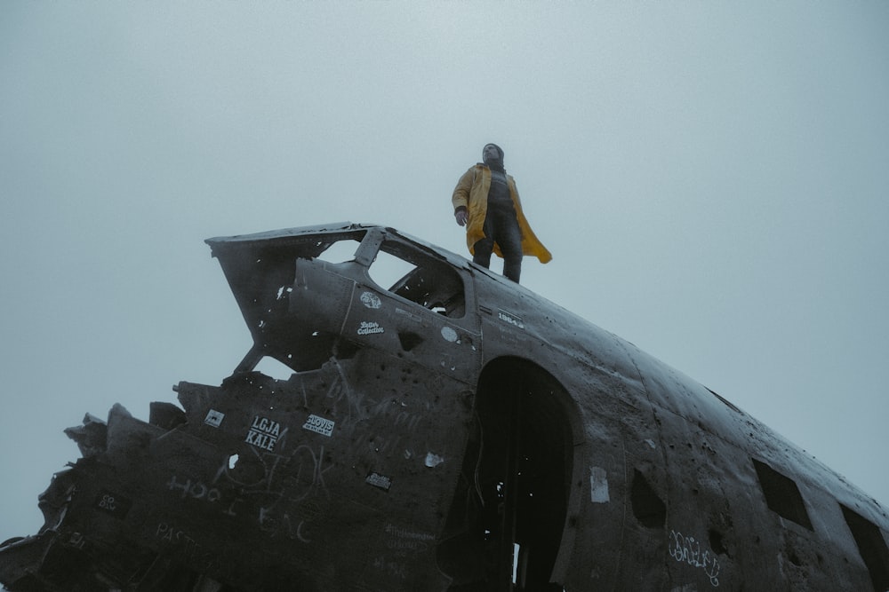man in yellow shirt standing on black jet plane