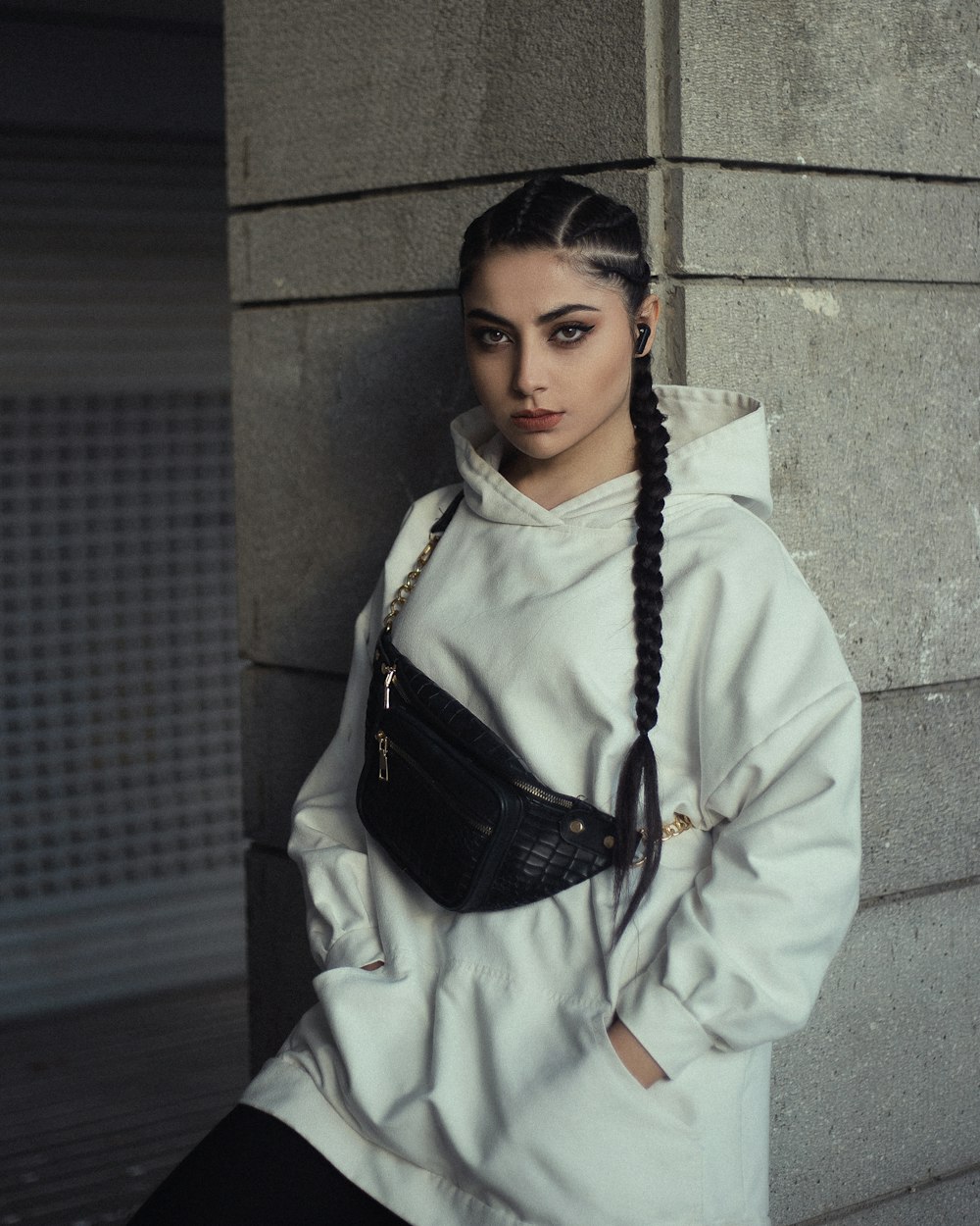 woman in white coat standing beside gray concrete wall