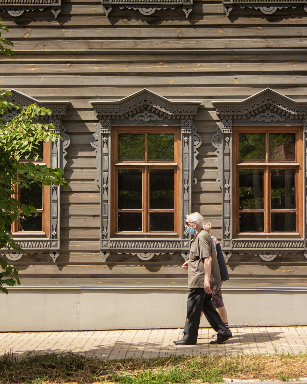 woman in gray coat standing in front of white wooden window