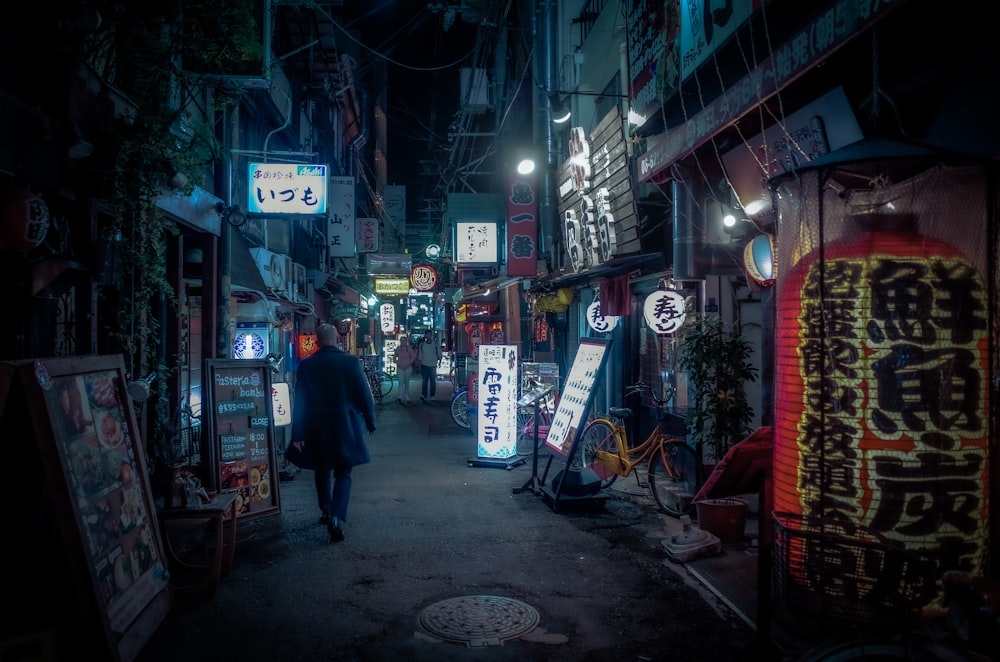 man in black jacket standing near store during nighttime