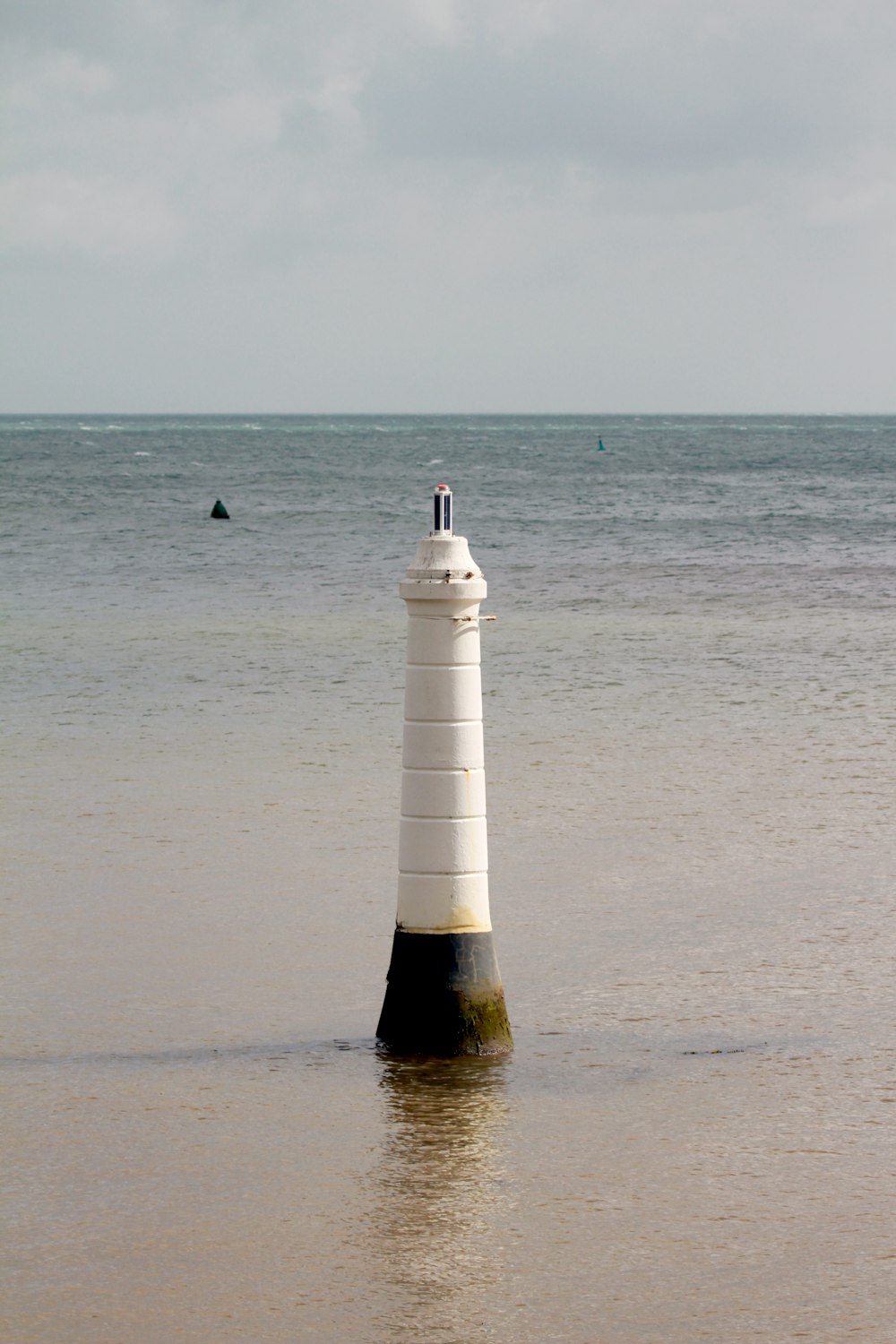 white and black lighthouse on beach during daytime