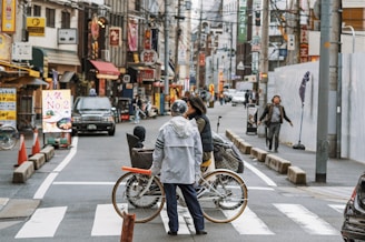 man in gray jacket riding bicycle on road during daytime