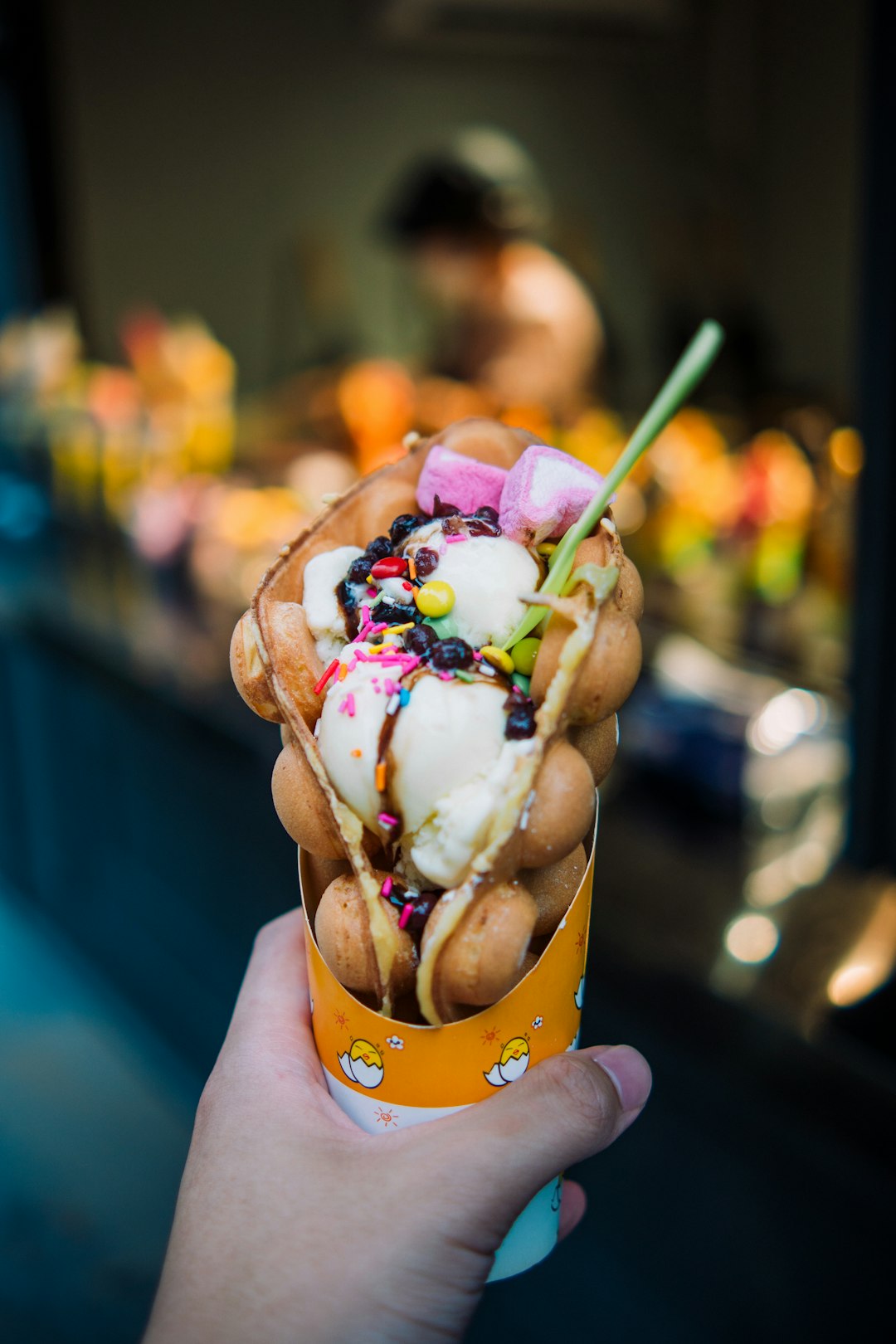 person holding ice cream cone with cherry and cherry