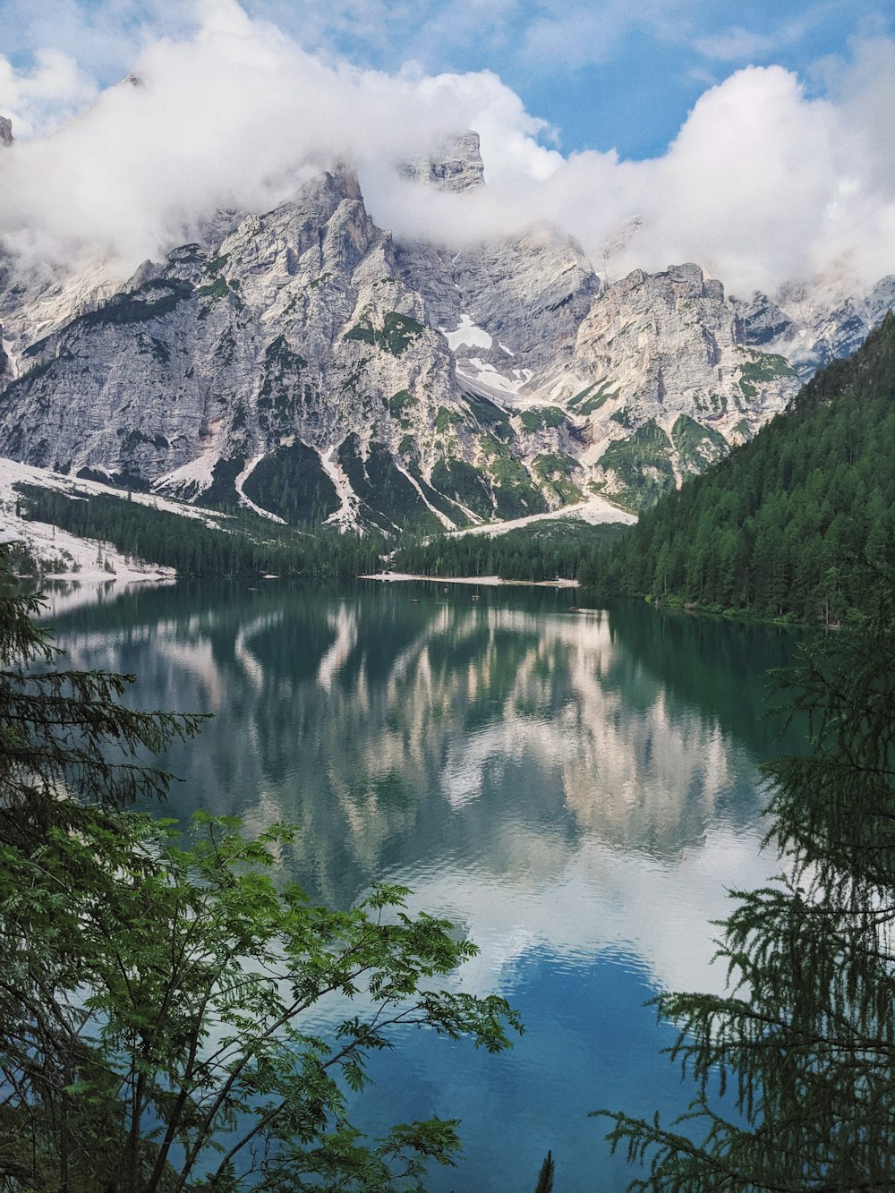 lake surrounded by green trees and snow covered mountain during daytime