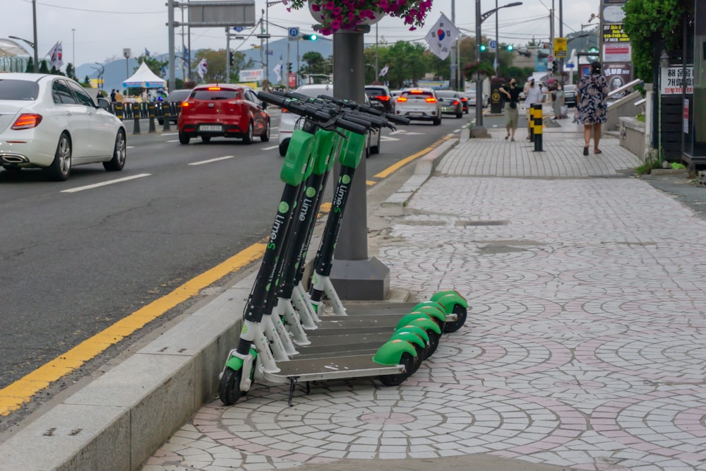 green and black metal stand on sidewalk during daytime