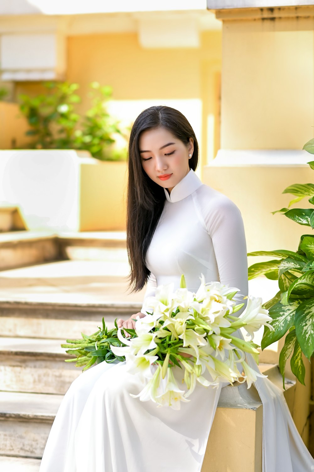 woman in white long sleeve dress holding white flowers