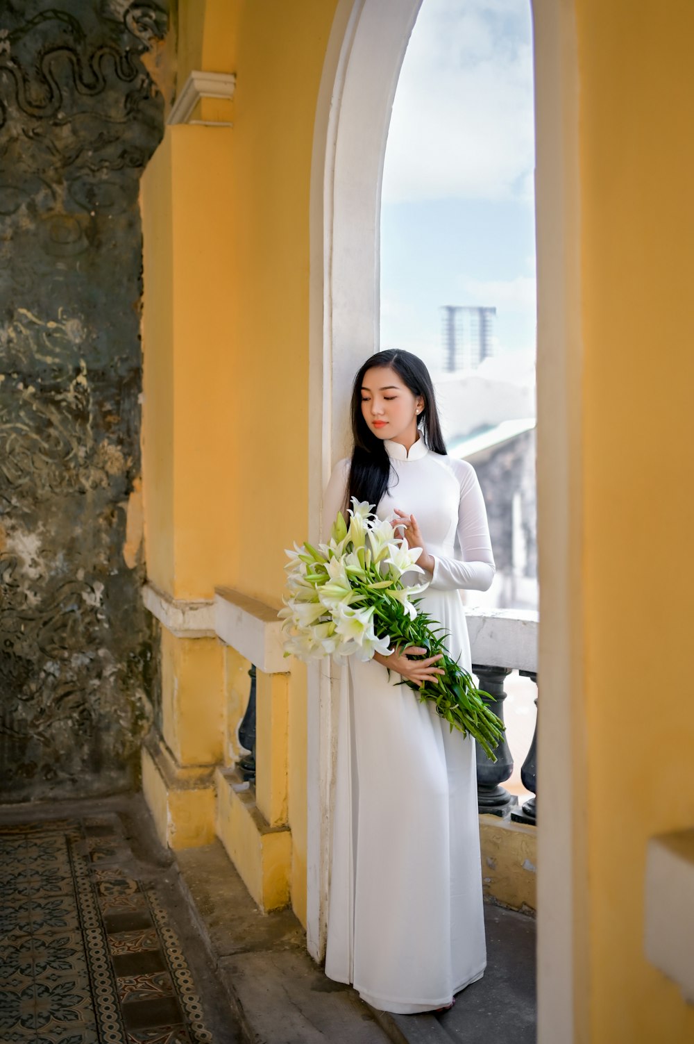 woman in white dress holding white flower bouquet