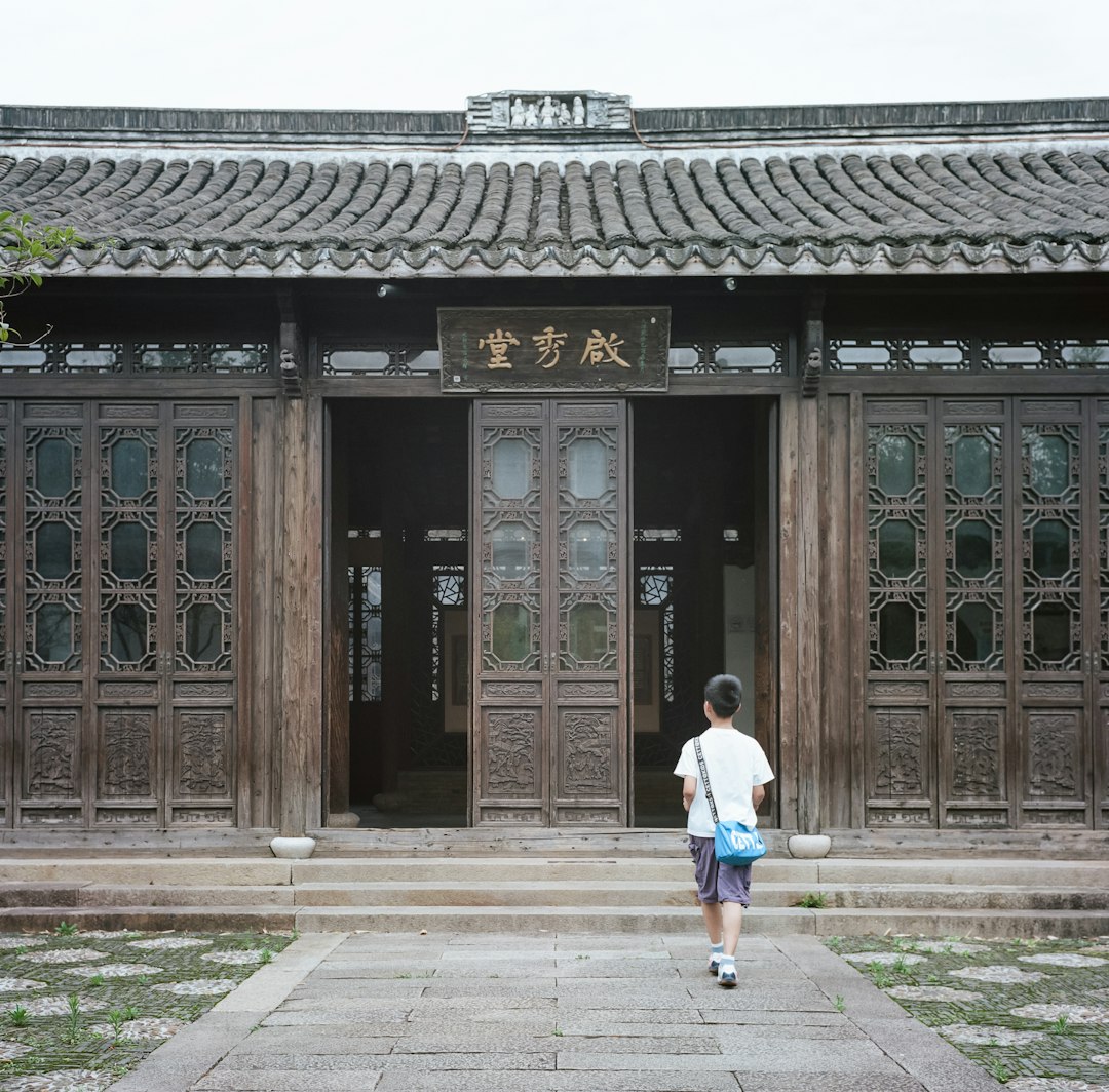 woman in white shirt and blue denim jeans walking on sidewalk near brown wooden building during