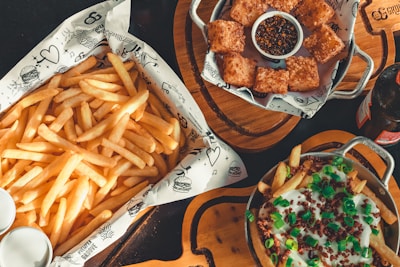 Side dishes including fries and dipping sauces served on a rustic wooden table.