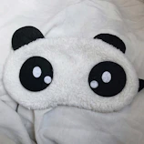 A blackout eye mask resting on a soft lavender-gray surface, inviting restful sleep.