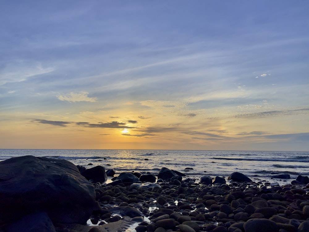 black rocks on sea shore during sunset