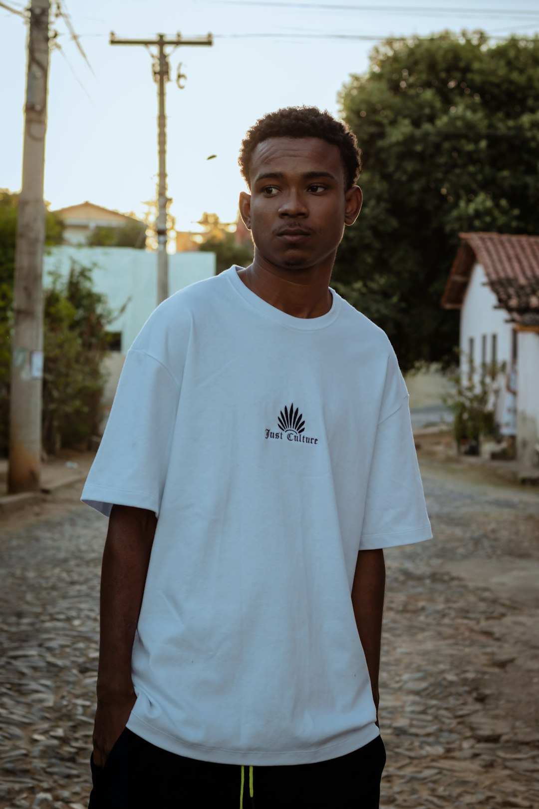 man in white crew neck t-shirt standing on gray concrete pavement during daytime