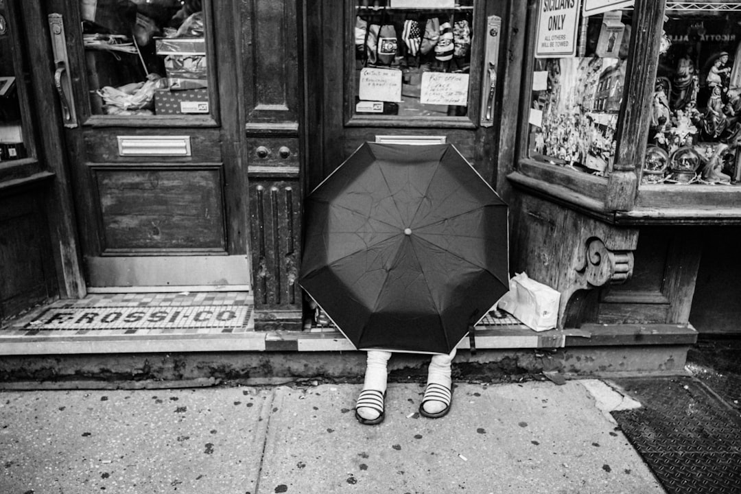 grayscale photo of person holding umbrella