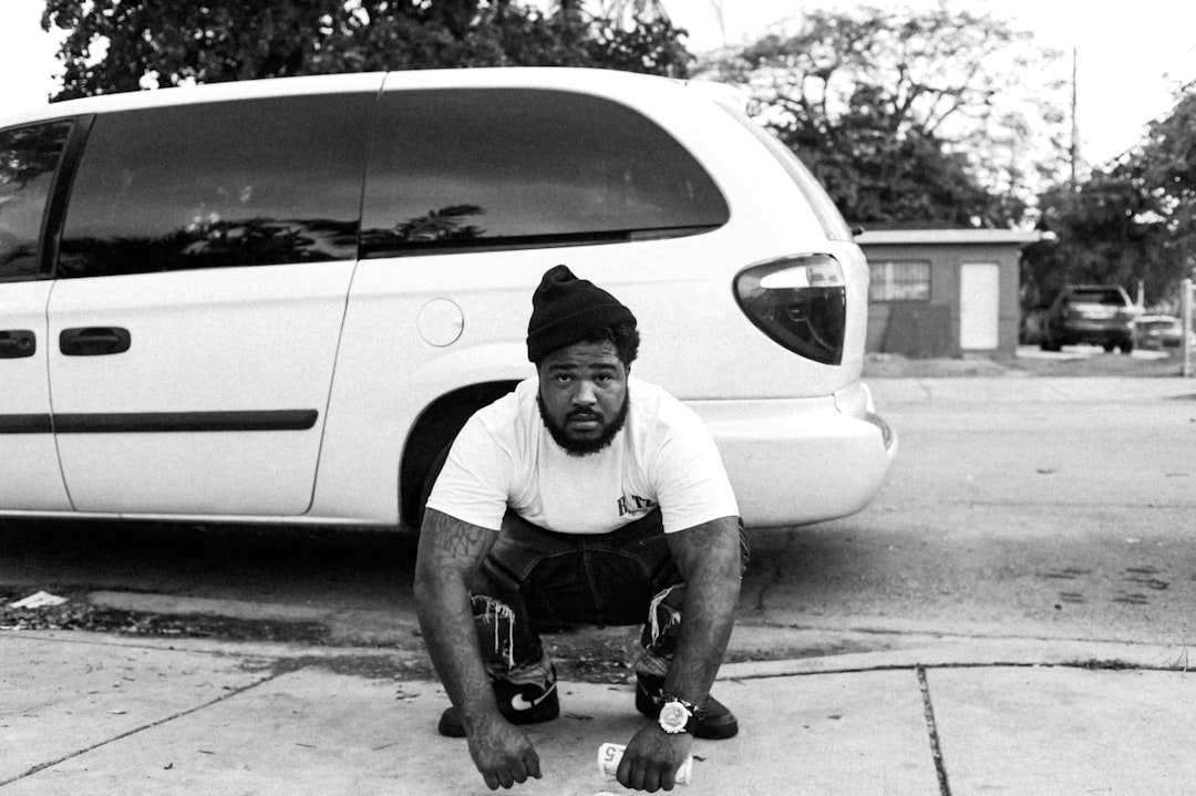 man in white t-shirt leaning on white car