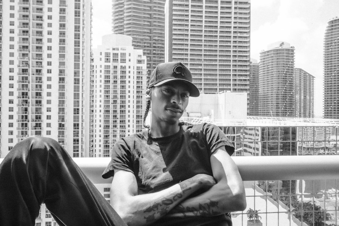 man in black crew neck t-shirt and black cap sitting on black chair