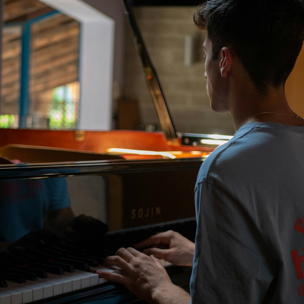 man in white shirt playing piano