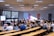 A lecture hall filled with students sitting in tiered rows, focusing on a presentation displayed on a large screen. Many students have laptops open, and some are wearing masks. Posters with 'SKEMA Business School' logos are visible on the walls.