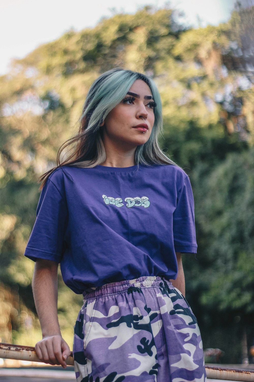 woman in blue crew neck t-shirt standing near green trees during daytime