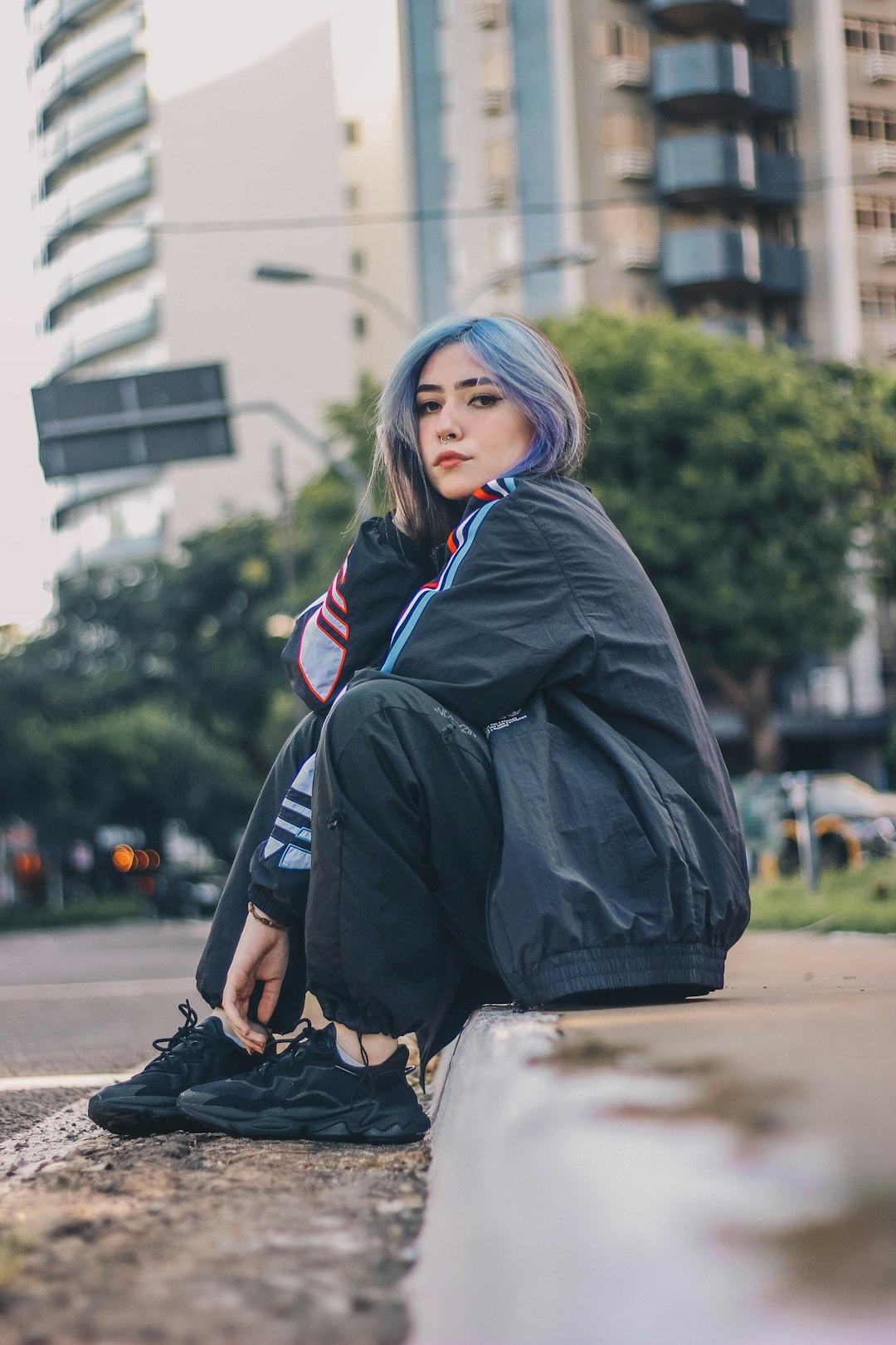 woman in black jacket and white pants sitting on concrete bench during daytime