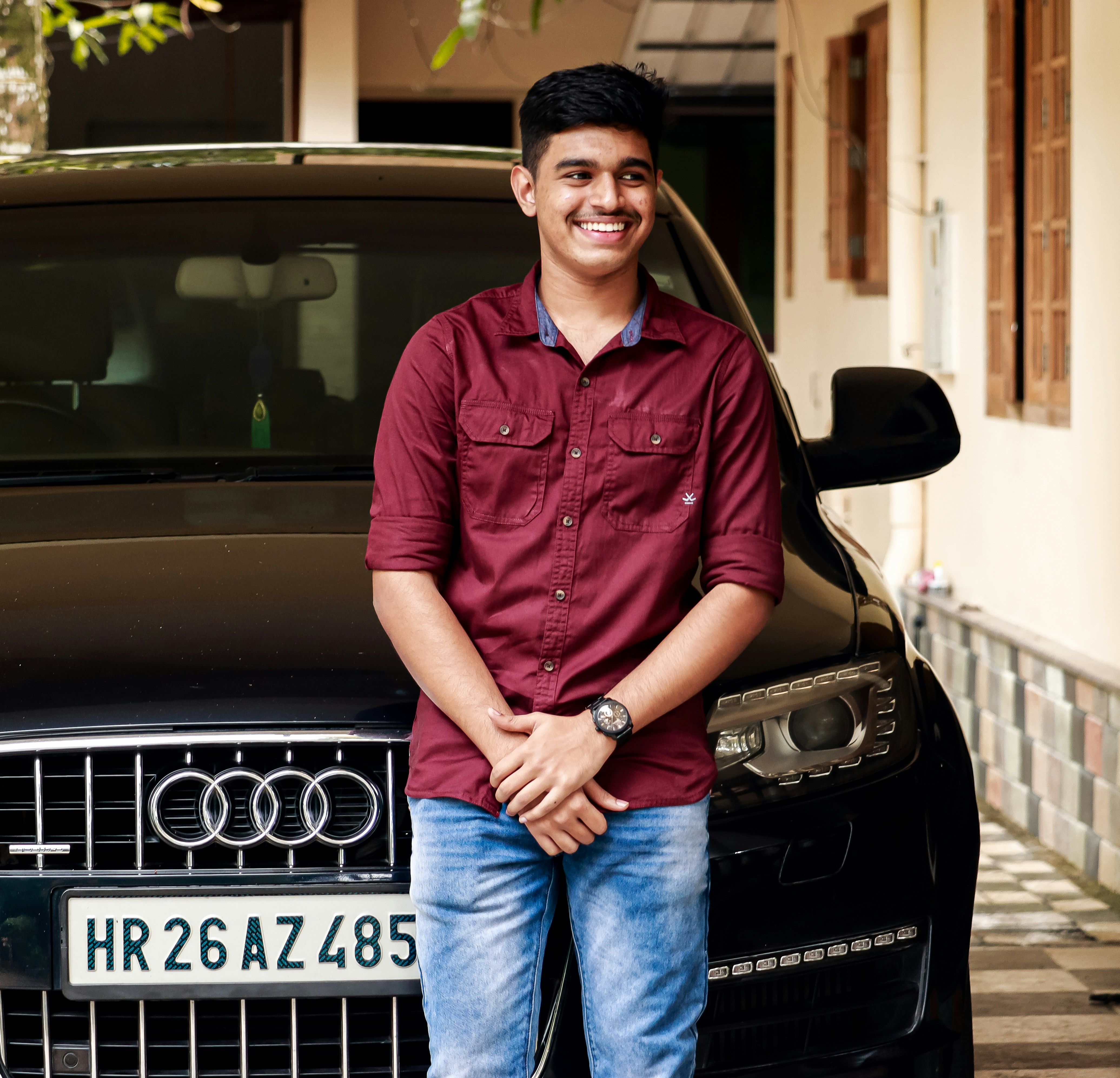 man in red button up shirt and blue denim jeans sitting on black mercedes benz car