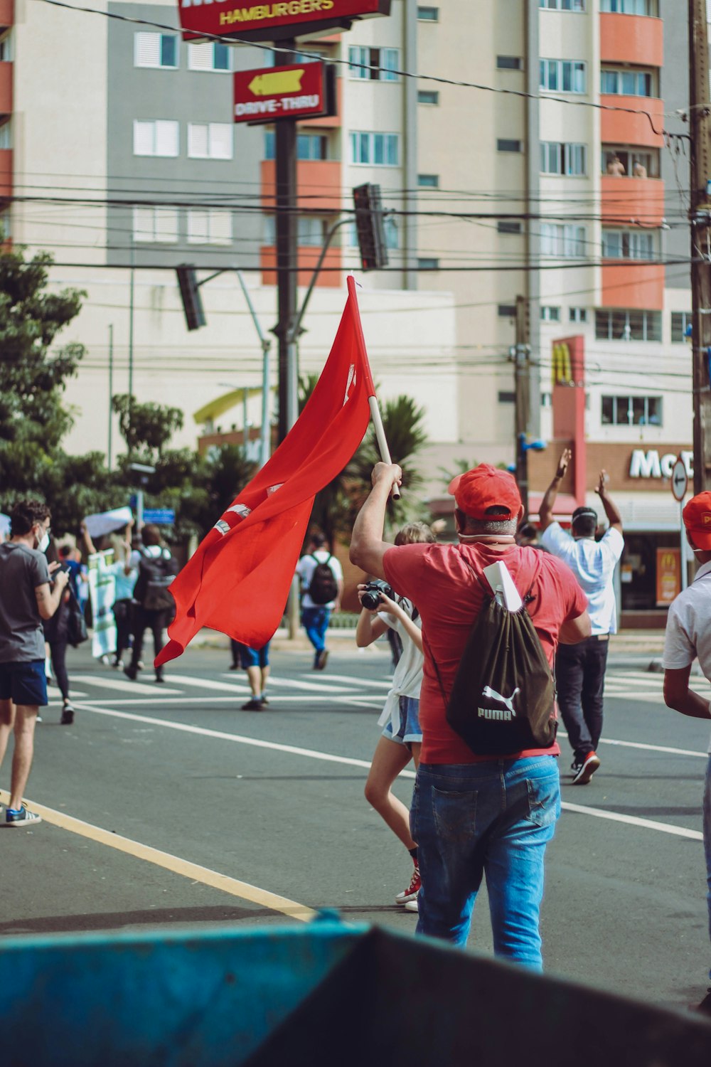 man in red and white shirt and blue denim jeans holding red flag