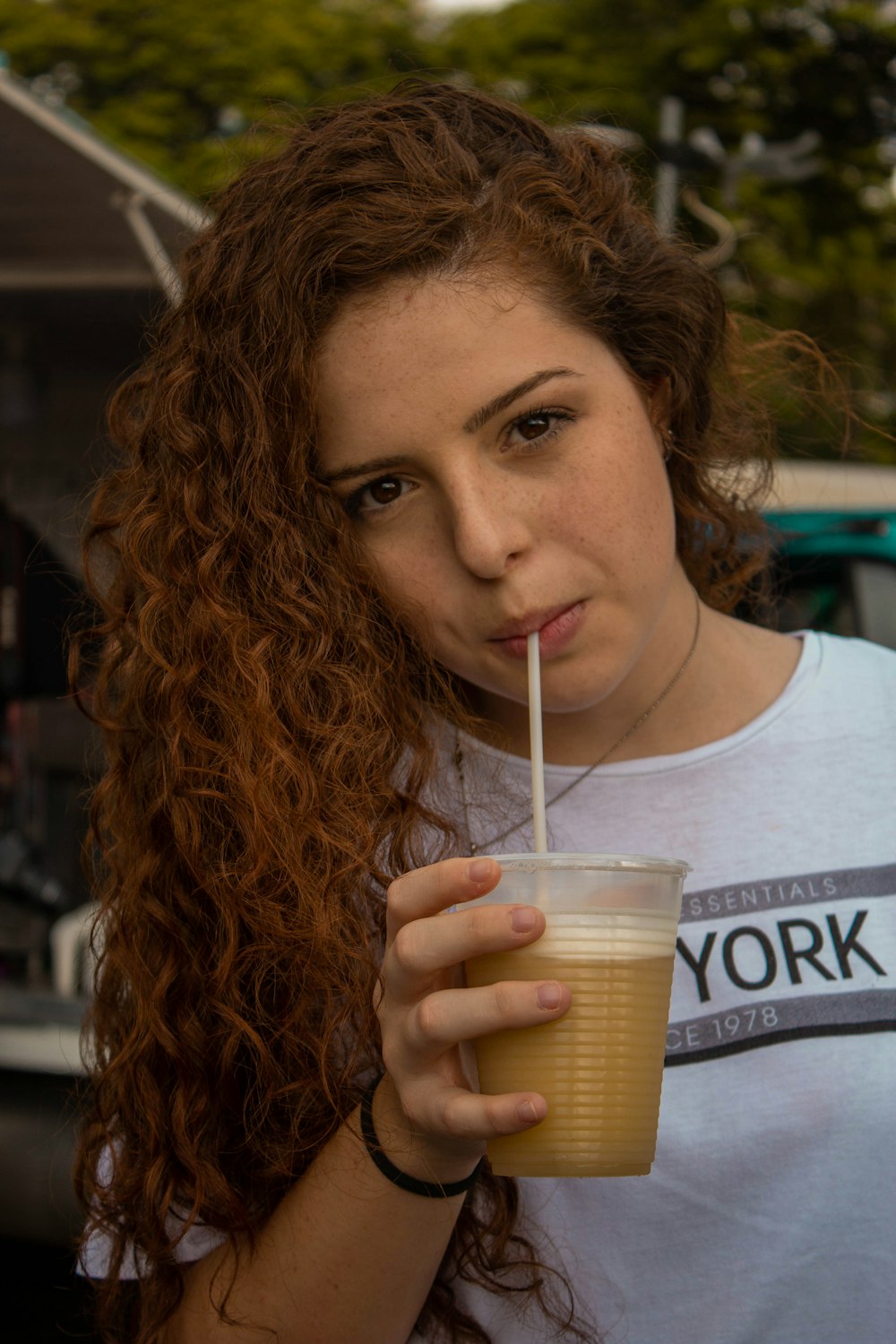 woman in white crew neck t-shirt sipping on clear plastic cup