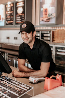 man in black polo shirt wearing black cap sitting on chair