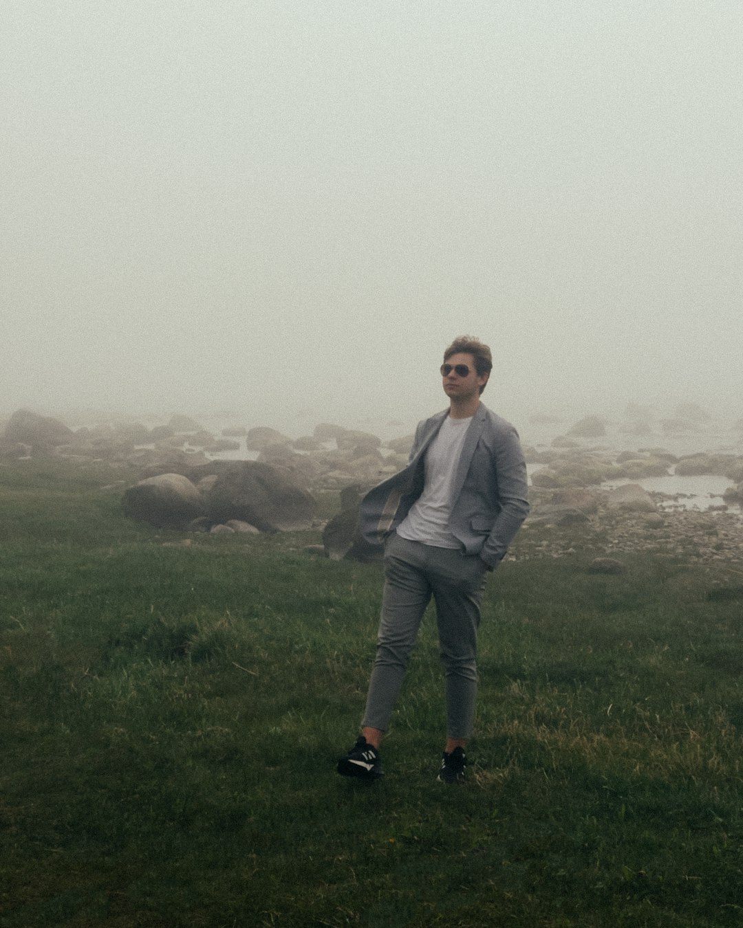 man in gray jacket standing on green grass field during daytime