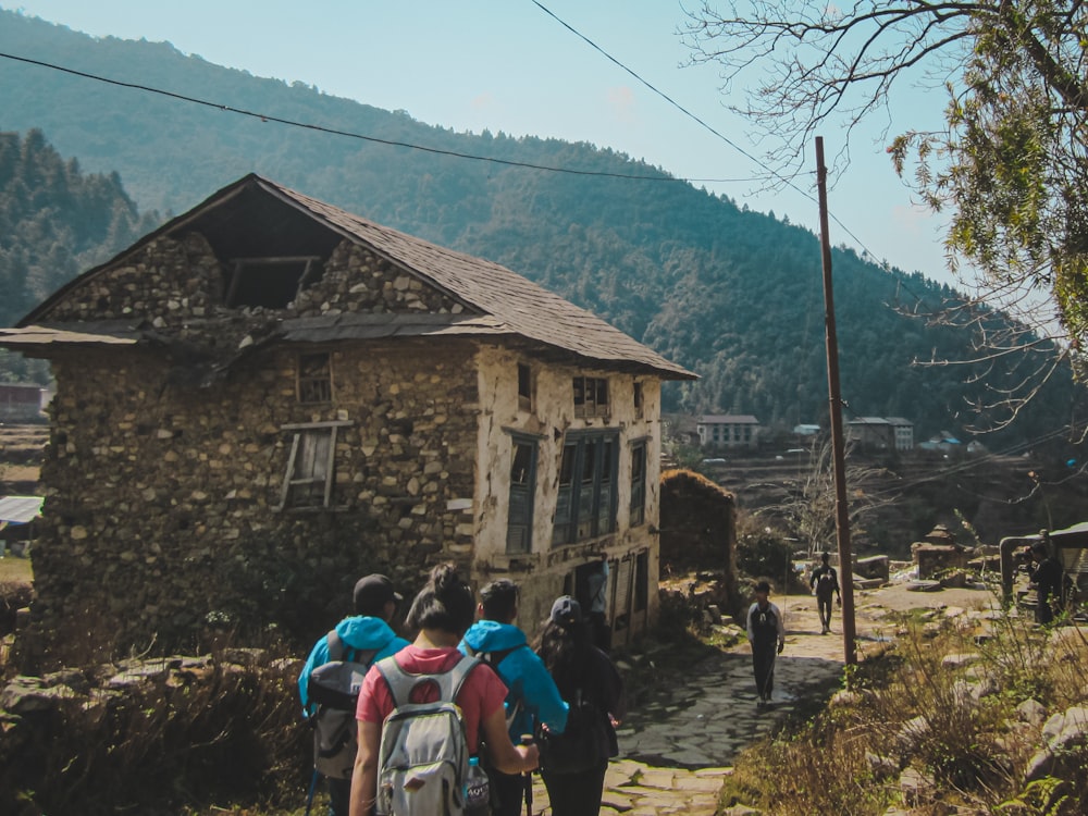 people walking on dirt road near brown wooden house during daytime